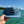 Blue cap held by a hand with a clear blue sky and ocean background