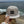 Beige cap with a brand logo held by a hand on a beach with ocean and sky in the background